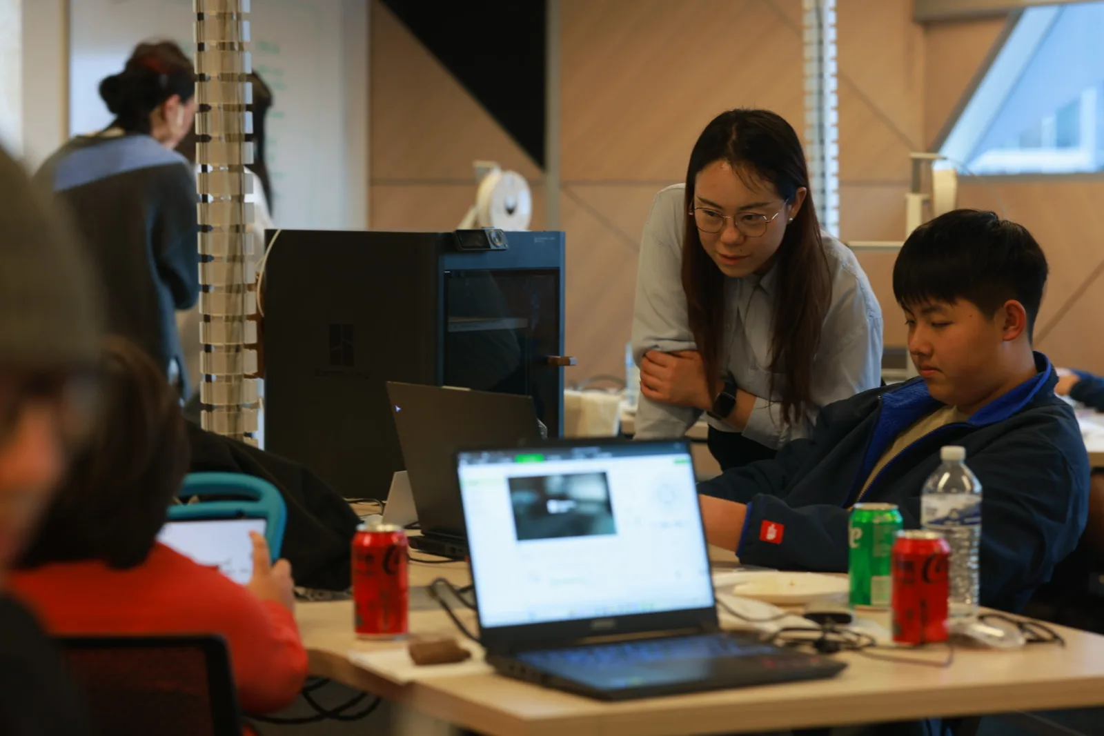 A mentor helping students work at a 3D printing station