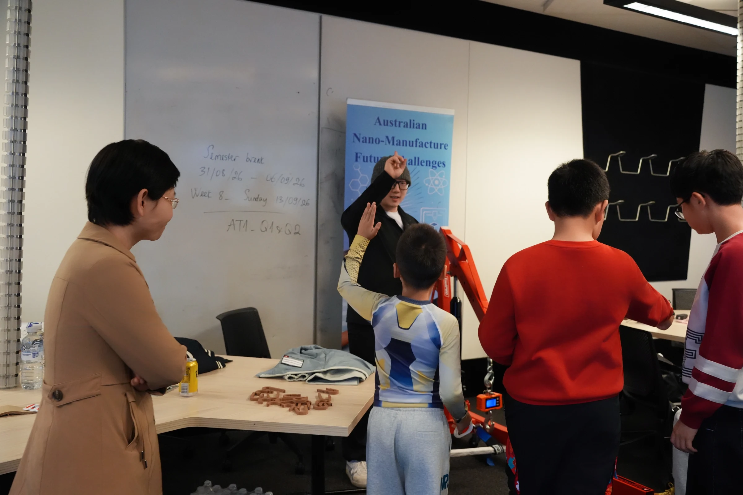 A mentor talking with students beside printed hook parts
